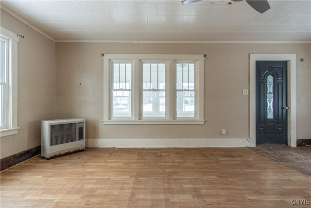 interior space with heating unit, crown molding, and light hardwood / wood-style flooring