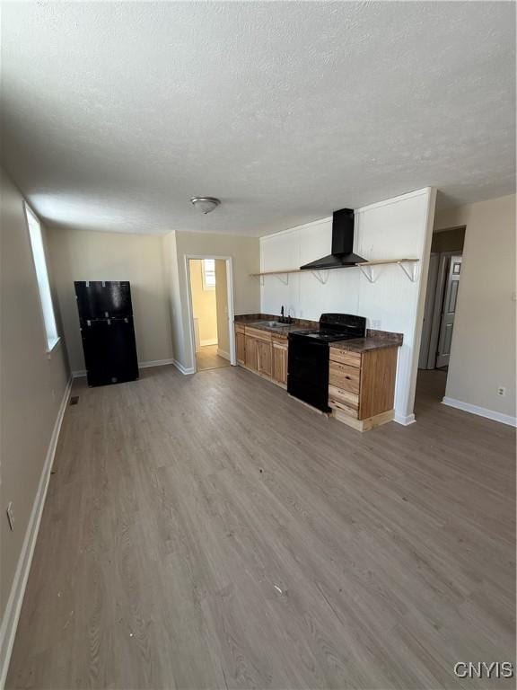 kitchen featuring black electric range oven, sink, light wood-type flooring, a textured ceiling, and wall chimney exhaust hood