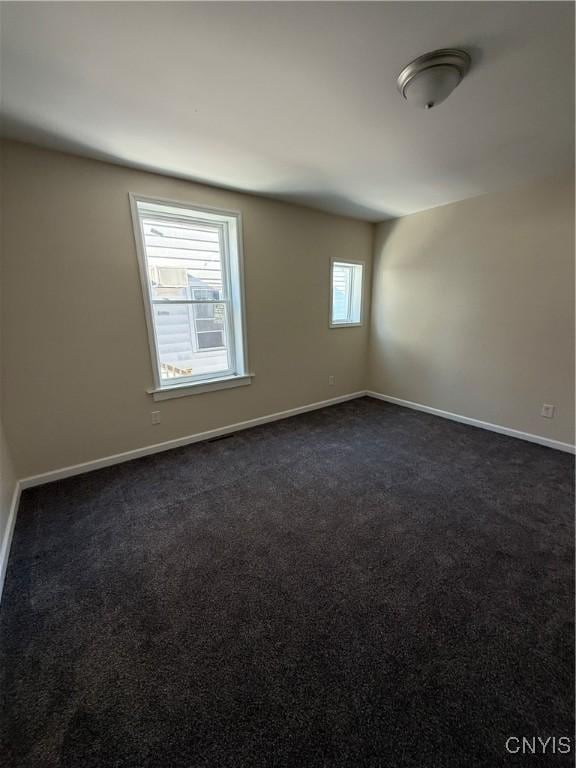 spare room with dark carpet