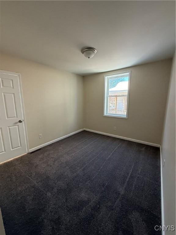 spare room featuring dark carpet