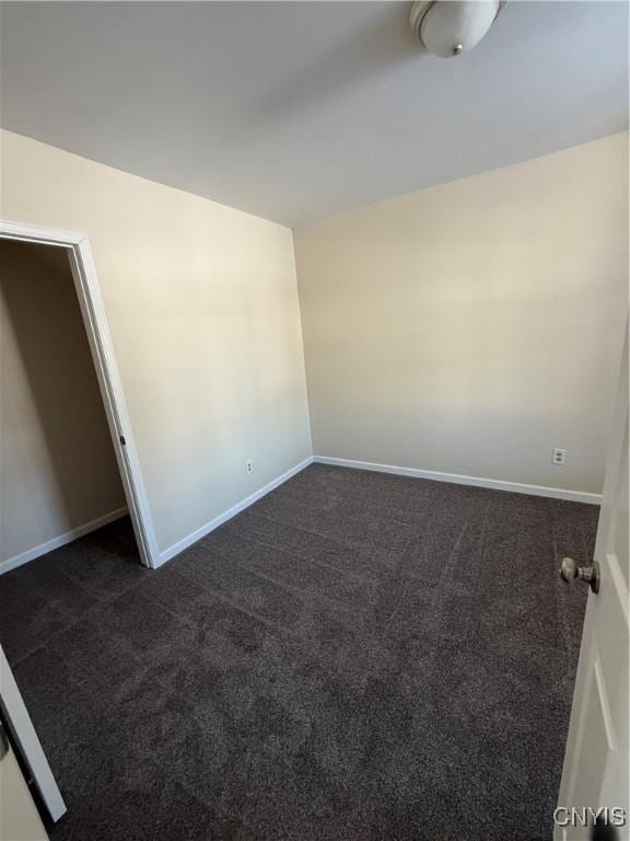 unfurnished room with dark colored carpet