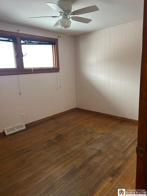 spare room featuring dark wood-type flooring and ceiling fan