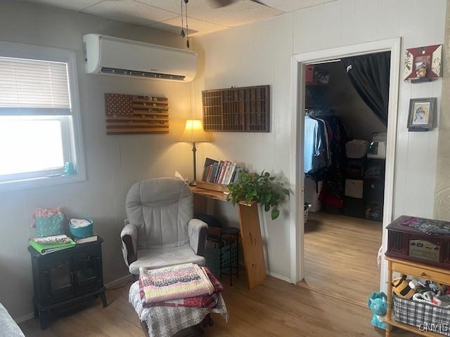 sitting room featuring a wall mounted air conditioner and light hardwood / wood-style floors