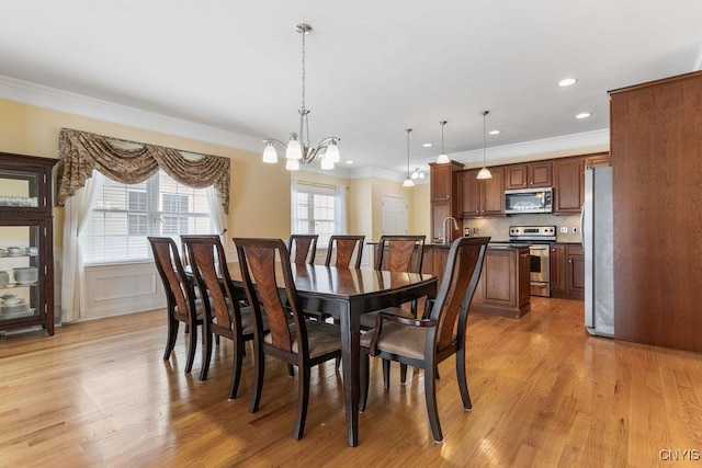 dining room featuring ornamental molding, sink, an inviting chandelier, and light hardwood / wood-style floors