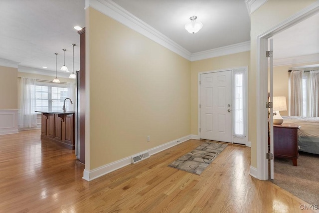 entryway with sink, crown molding, and light hardwood / wood-style floors