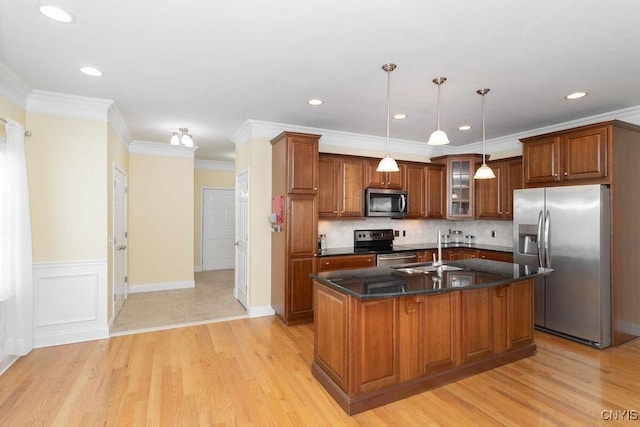 kitchen with sink, hanging light fixtures, a center island with sink, ornamental molding, and stainless steel appliances