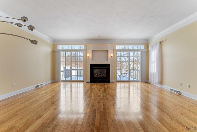 unfurnished living room with ornamental molding, plenty of natural light, and light hardwood / wood-style floors