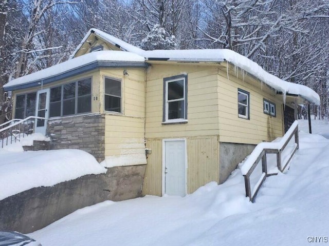 snow covered property with a sunroom