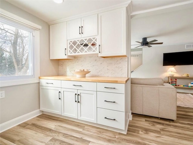 bar with wooden counters, white cabinets, light wood-type flooring, and decorative backsplash