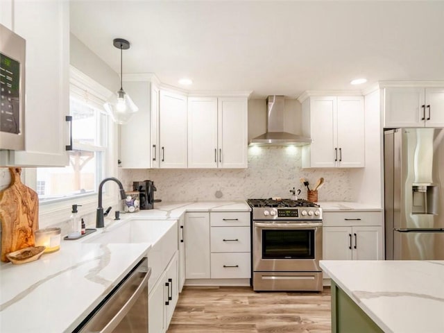 kitchen featuring white cabinets, appliances with stainless steel finishes, and wall chimney range hood