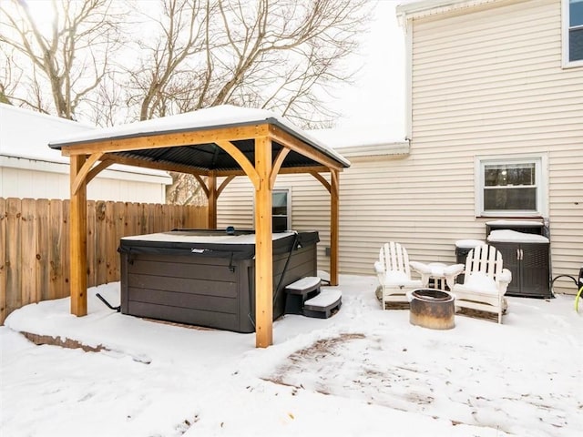 snow covered patio featuring a gazebo, an outdoor fire pit, and a hot tub