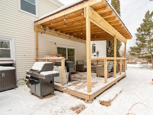 snow covered patio with a wooden deck and outdoor lounge area