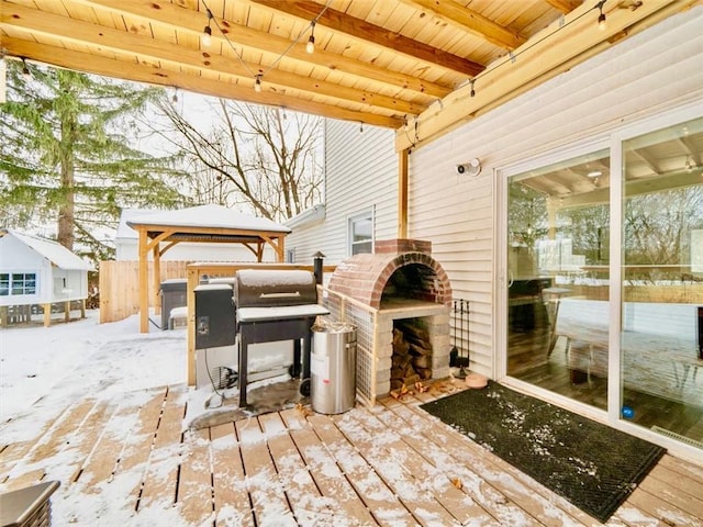 snow covered deck featuring an outdoor brick fireplace, a gazebo, and grilling area