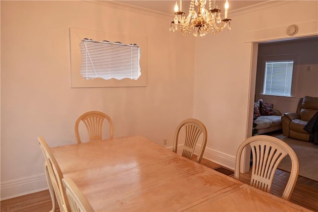 dining area featuring hardwood / wood-style flooring, ornamental molding, and a notable chandelier