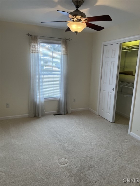 unfurnished bedroom with ceiling fan, light carpet, and a closet