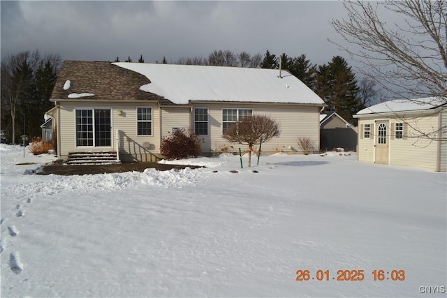 snow covered rear of property featuring an outdoor structure