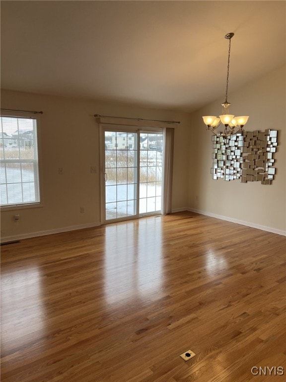 spare room featuring a notable chandelier and hardwood / wood-style floors