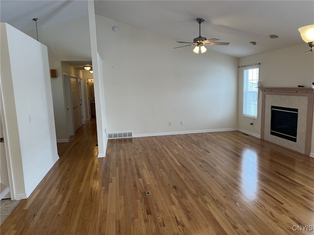 unfurnished living room with hardwood / wood-style flooring, vaulted ceiling, ceiling fan, and a fireplace