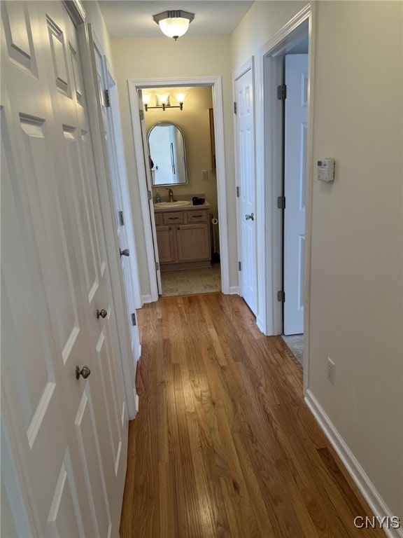 hallway with sink and light wood-type flooring