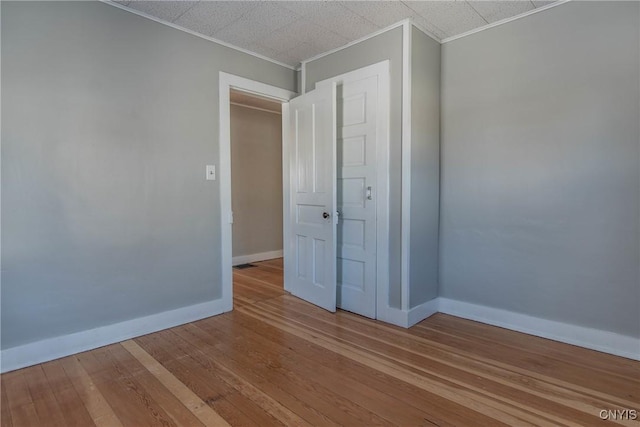 unfurnished bedroom featuring crown molding and wood-type flooring