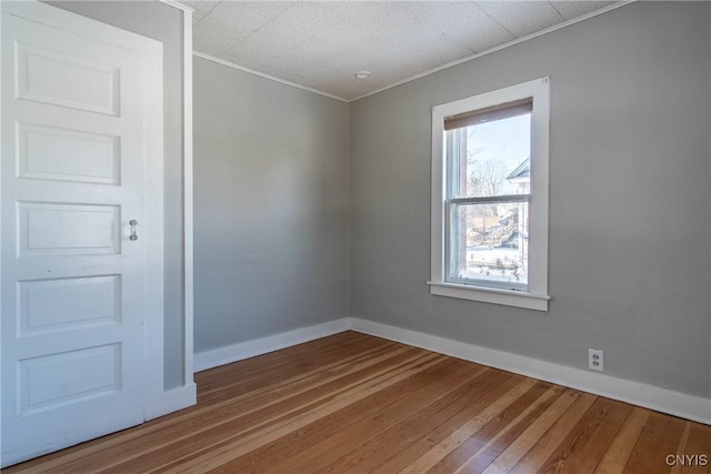 unfurnished room with wood-type flooring and ornamental molding