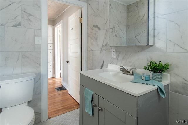 bathroom featuring tile walls, vanity, ornamental molding, and toilet