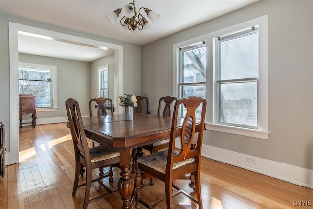 dining space with a healthy amount of sunlight, an inviting chandelier, and light hardwood / wood-style floors