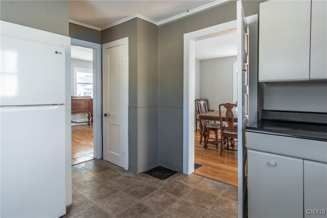 kitchen with white cabinetry, crown molding, and white refrigerator