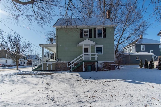 snow covered rear of property featuring cooling unit