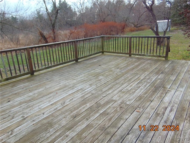 wooden deck with a storage unit and a lawn