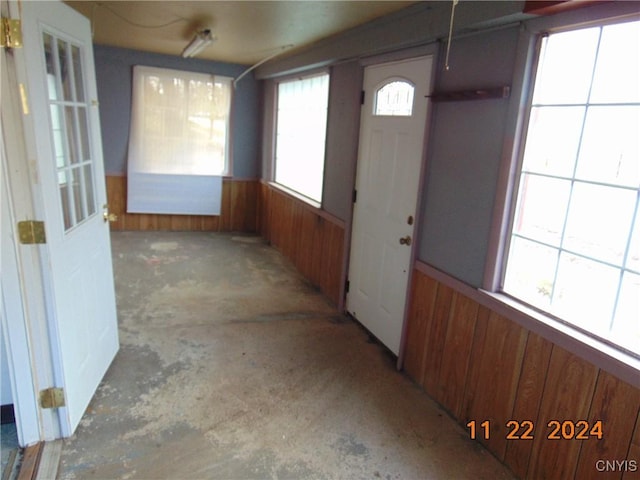 foyer entrance featuring wooden walls and concrete flooring