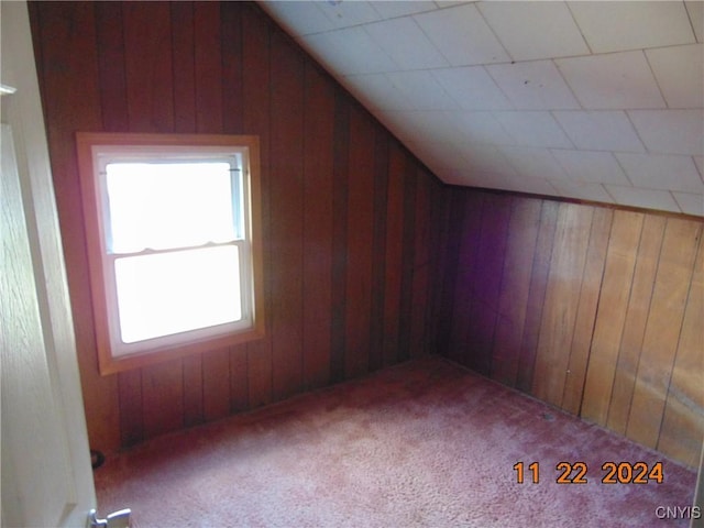 additional living space with plenty of natural light, carpet floors, and wooden walls