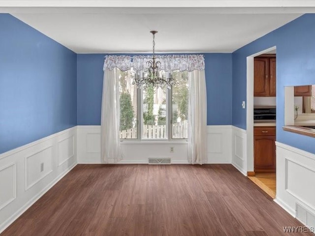 unfurnished dining area with a notable chandelier and hardwood / wood-style flooring