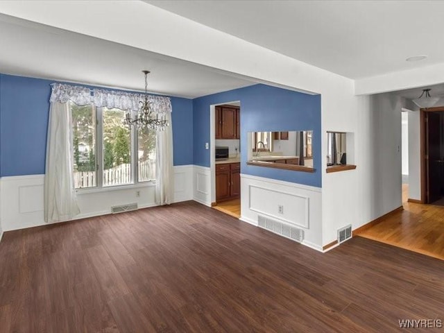 unfurnished living room with hardwood / wood-style flooring and an inviting chandelier