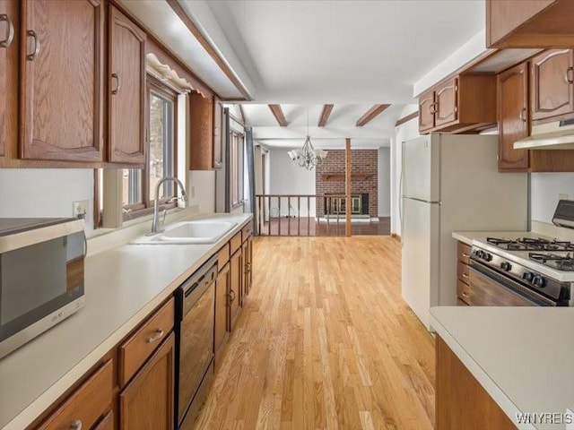 kitchen featuring sink, light hardwood / wood-style flooring, stove, an inviting chandelier, and black dishwasher