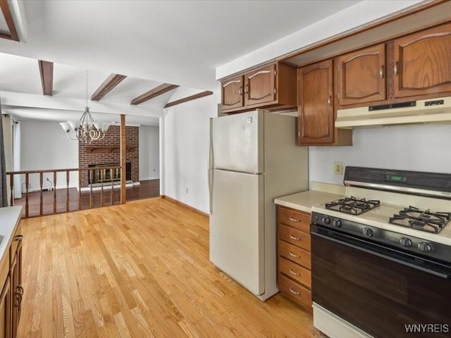 kitchen with beamed ceiling, hanging light fixtures, white appliances, light hardwood / wood-style floors, and an inviting chandelier