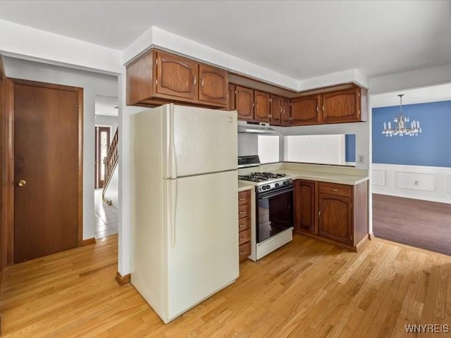 kitchen featuring white appliances, a chandelier, light hardwood / wood-style floors, and hanging light fixtures