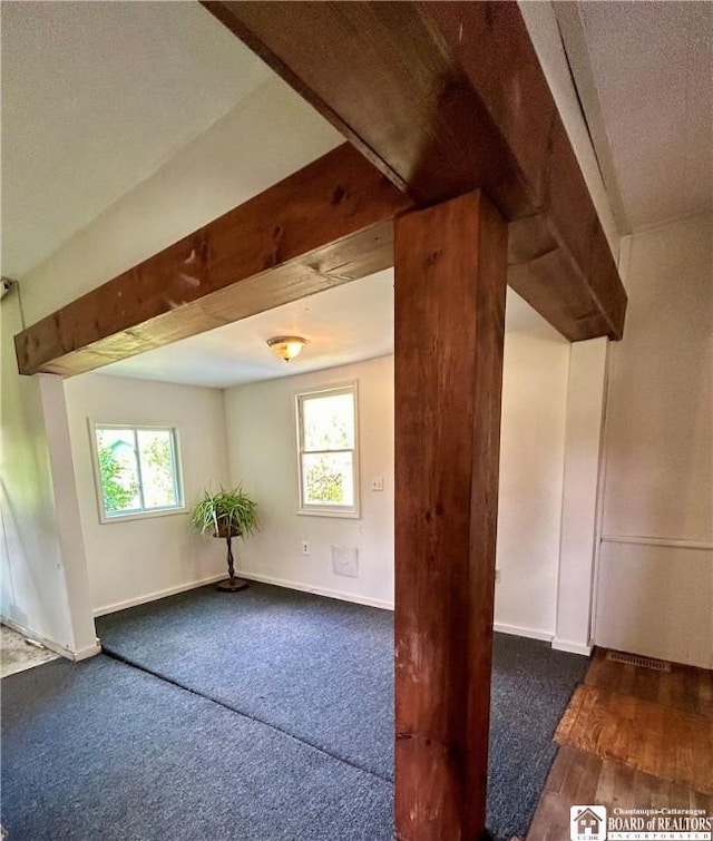 bonus room featuring dark carpet and plenty of natural light