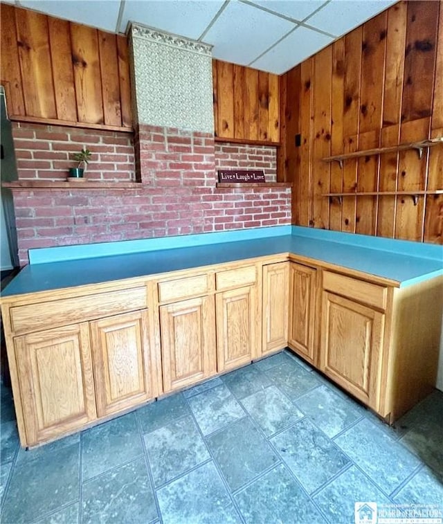 kitchen with a paneled ceiling and wood walls