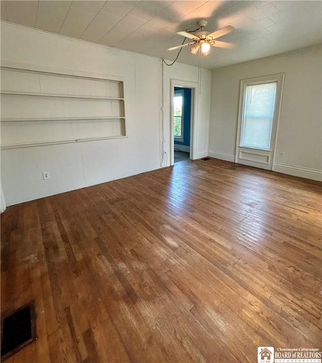 unfurnished living room with wood-type flooring, ceiling fan, and built in shelves