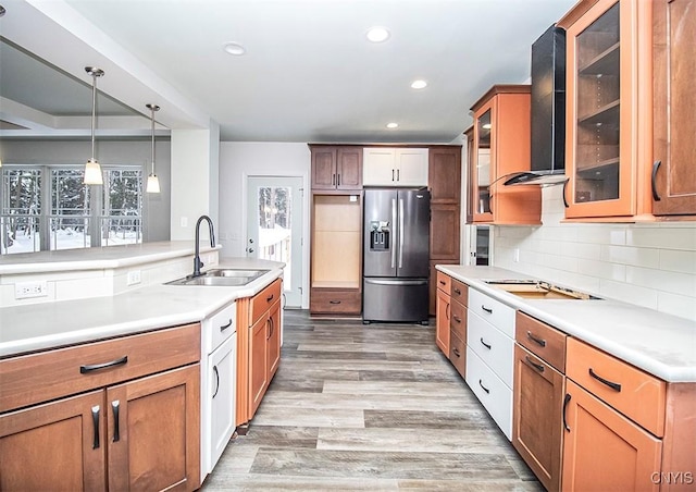 kitchen featuring decorative light fixtures, tasteful backsplash, sink, stainless steel fridge with ice dispenser, and wall chimney range hood