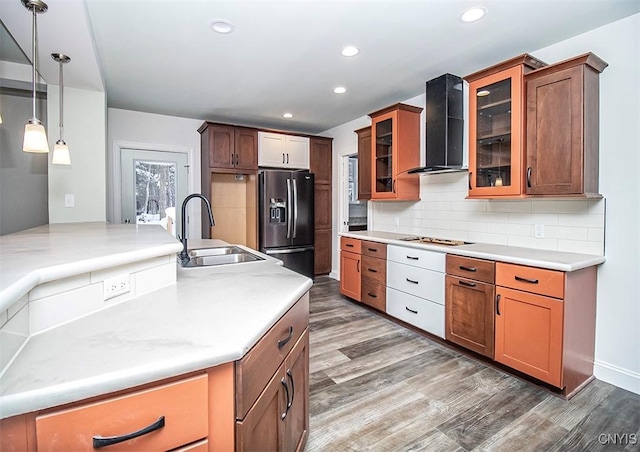 kitchen featuring sink, stainless steel refrigerator with ice dispenser, decorative backsplash, decorative light fixtures, and wall chimney exhaust hood