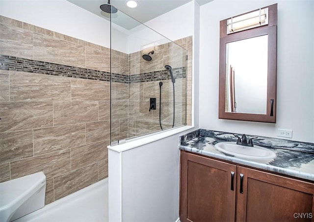 bathroom with a tile shower, vanity, and toilet