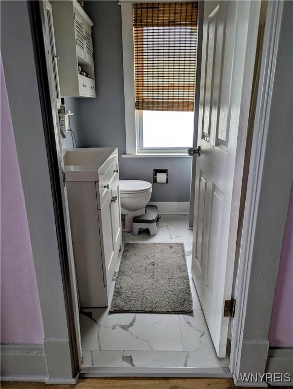 bathroom with baseboards, toilet, marble finish floor, and vanity