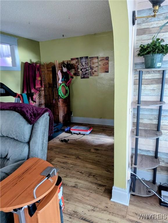 living area featuring wood finished floors, baseboards, and a textured ceiling