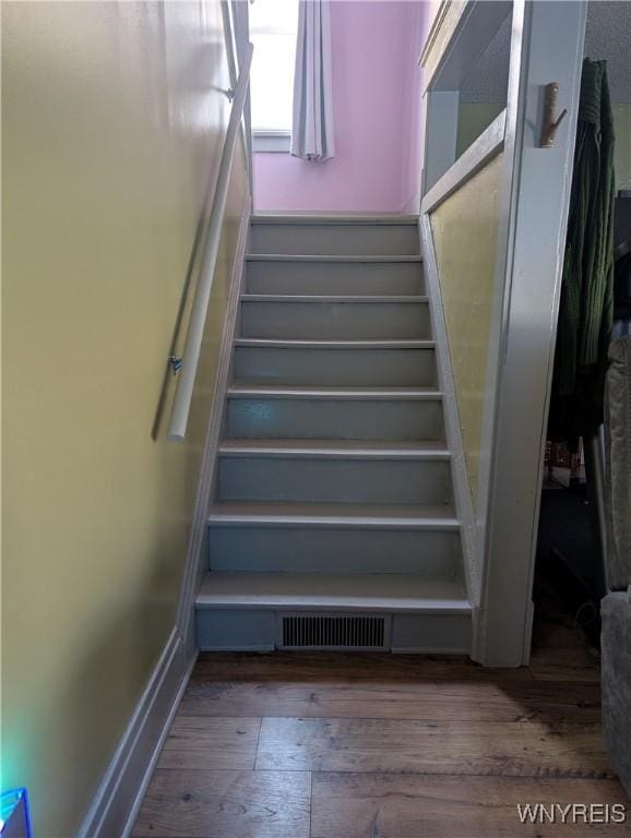 staircase with visible vents, baseboards, and wood finished floors