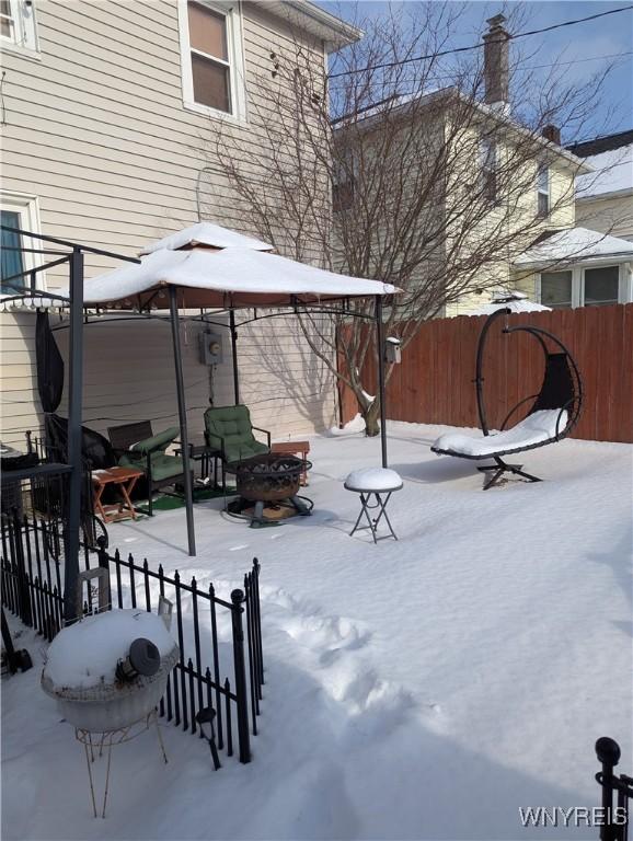 snowy yard with a patio, an outdoor fire pit, and fence