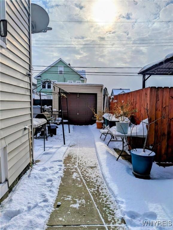 snow covered patio featuring an outbuilding and fence