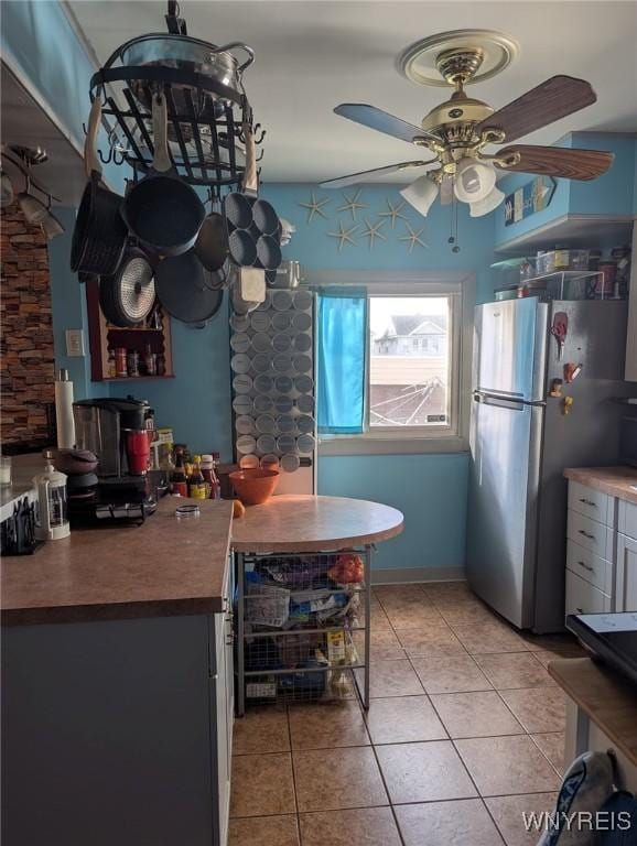 kitchen featuring light tile patterned floors, wooden counters, freestanding refrigerator, and a ceiling fan