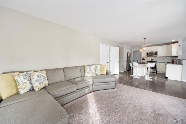 living room featuring dark hardwood / wood-style flooring, a notable chandelier, and sink